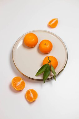 Taze mandalina ya da bej bir tabakta altın kenarlı mandalinalı meyveler. Renkli meyve arka planı. Dekoratif noel kompozisyonu