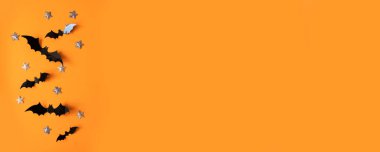 Cadılar Bayramı düz konum siyah kağıt yarasalar uçar ve turuncu arka planda altın yıldızlar, üst görünüm.