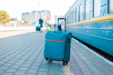 Şehir caddesindeki tren istasyonunda mavi seyahat valizi. Macera, keşif, ulaşım ve seyahat teması konsepti.