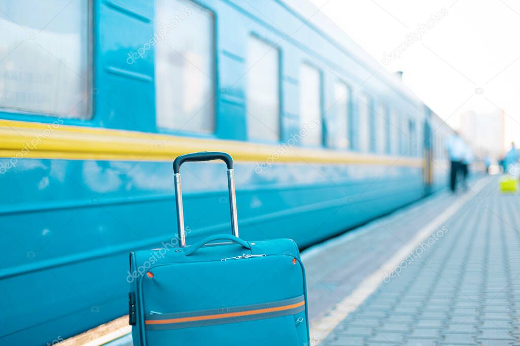 Blue travel luggage on train station near railway on the city street. Adventure, discovery, transport and travel theme concept background.