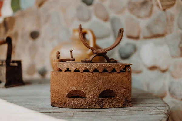 Close up of an antique old rusty non electric iron for ironing on wood table background. Houseworks.