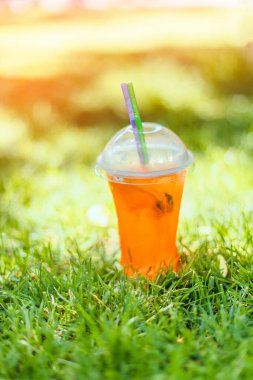Sıcak bir günde, yeşil çimlerin üzerinde parlak, soğuk bir yaz içeceği