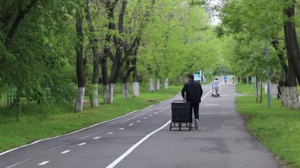 Joven trabajador en uniforme especial transporta un contenedor de basura de plástico negro con residuos. Basura de plástico. Salvar el planeta — Vídeos de Stock