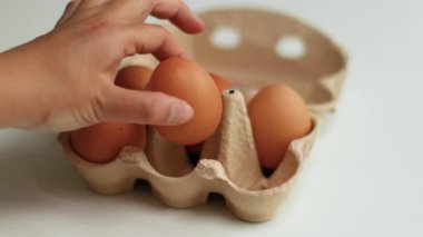 Kahverengi organik tavuk yumurtaları beyaz masaya koyulmuş kahverengi kağıt tepside. Sağlıklı gıda ve organik protein kahvaltı konsepti