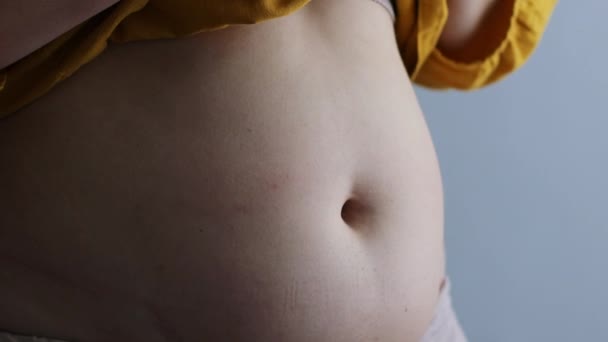 太りすぎの女性は彼女の脂肪腹に触れる。灰色の背景に過剰な腹の脂肪。フィットネス、栄養や肥満、健康の概念 — ストック動画