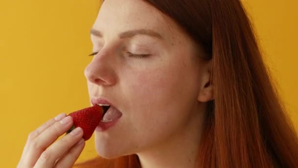 Gelukkige jonge vrouw proeven van verse aardbeien, genieten van verse biologische snack, gezond eten en lifestyle concept — Stockvideo