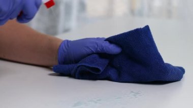 Evde dezenfektan spreyi ve mikrofiber bezle temizlik yapan bir kadın var. Dezenfeksiyon ve covid-19 'un önlenmesi kavramı.