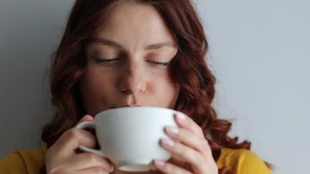 Gelukkige en positieve vrouw die 's morgens een slokje koffie drinkt van een mok. — Stockvideo