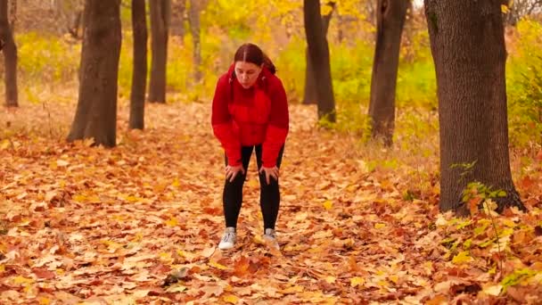 Müde Läuferin wischt sich nach Training im Herbstpark den Schweiß ab — Stockvideo