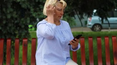 Çekici, başarılı ve mutlu orta yaşlı kadın cep telefonunu mesajlaşma ya da sosyal medya için kullanıyor, internetten internet üzerinden satın alıyor.