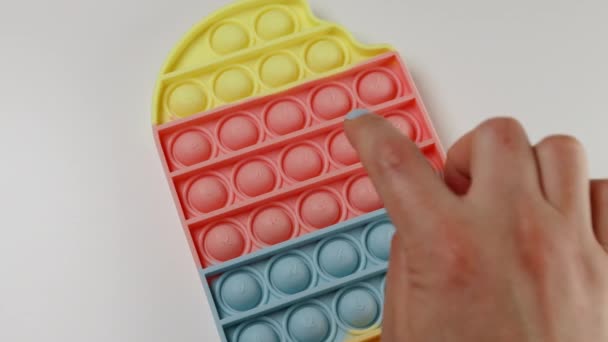 Childs mano preme su pop it silicone giocattolo su uno sfondo grigio. — Video Stock