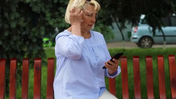 Çekici, başarılı ve mutlu orta yaşlı kadın cep telefonunu mesajlaşma ya da sosyal medya için kullanıyor, internetten internet üzerinden satın alıyor. — Stok video