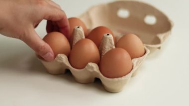 Kahverengi organik tavuk yumurtaları beyaz masaya yerleştirilmiş kahverengi karton bir kutuda. Çevre dostu yumurta üretimi.