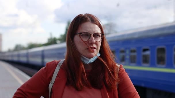 Niezadowolona młoda dziewczyna zdjęła ochronną maskę medyczną na peronie stacji kolejowej — Wideo stockowe