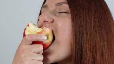 Pozitif kadın portresi, en sevdiği elmayı yerken keyifli bir şekilde gülümser, zevkten gözlerini kapatır. Yazın Meyve.