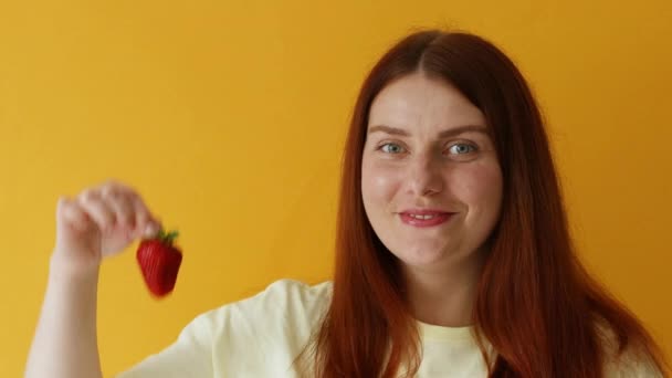 O retrato da mulher sorri no bom humor como come a sobremesa favorita mantém a baga vermelha. Deliciosa sobremesa de morango. Alimentação saudável e conceito de estilo de vida — Vídeo de Stock