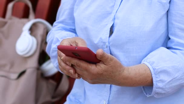 Обрезанное видео рук взрослых бизнесвумен с помощью смартфона устройство с 5g интернет-серфинг веб сидя на открытом воздухе в парке. — стоковое видео