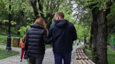 Şehir parkında sokakta yürüyen mutlu aile insanlarının arka görüntüsü..