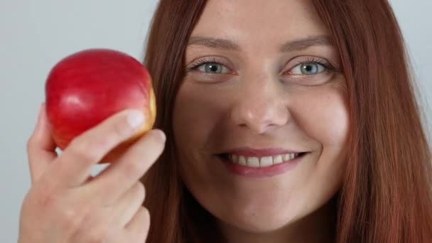 灰色の背景に隔離された新鮮な熟れた赤いリンゴの果実を手に持つ陽気な若い女性。休暇のコンセプトをリラックス. — ストック動画
