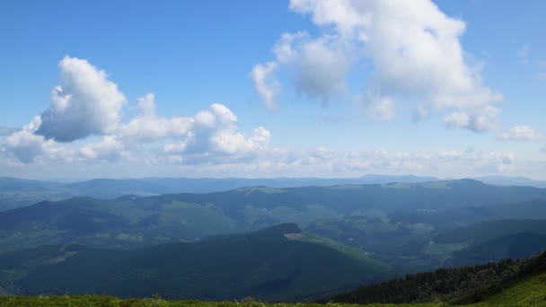 Zapierający dech w piersiach panoramiczny widok na pagórki krajobraz z kwitnących łąk i szczytów górskich na słoneczny dzień tło z niebieskim niebem i chmury w lecie — Wideo stockowe