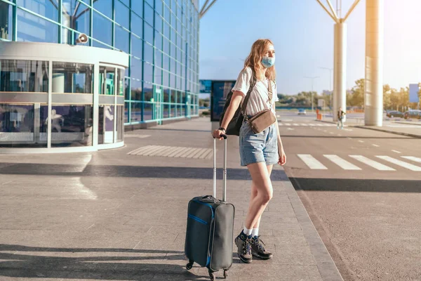 COVID-19 reizen luchthaven vrouw toerist met rugzak en koffer staan in de buurt van de internationale luchthaven terminal te wachten voor boarding. Vakantie annuleringen als gevolg van coronavirus reisbeperkingen. — Stockfoto