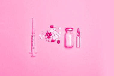 Şırınga, antibiyotik ilaç şişesi, haplar, pembe arka planda fotokopi alanı olan haplar.