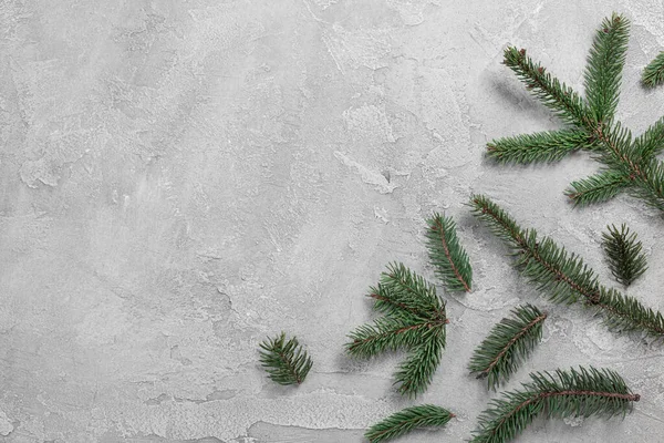 Composición minimalista de vacaciones con ramas de abeto fresco sobre fondo textural gris con lugar para el texto — Foto de Stock