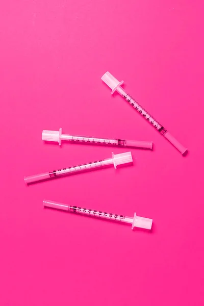 ピンクの背景に薄い化粧品注射器の多く — ストック写真
