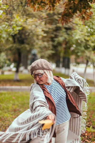 Kaukasische Seniorin in warmer Freizeitkleidung und einem kuscheligen Schal, die im Freien Spaß hat und die Natur genießt — Stockfoto