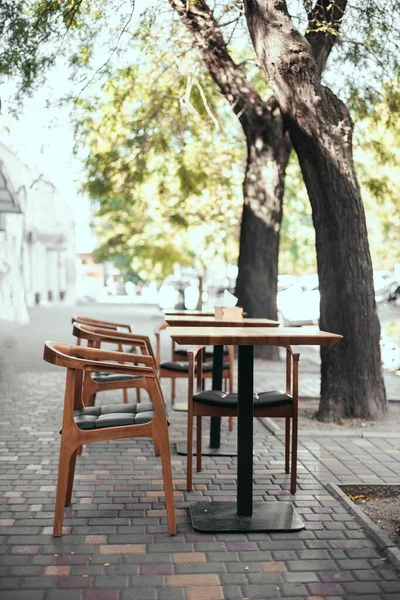 Outdoor empty street restaurant with wood stile chairs in summer on city street. Coronavirus crisis