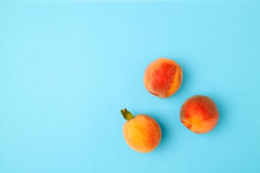 Taze kırmızı şeftaliler ve parlak mavi arka planda yapraklar yazı ve afiş için yer var. Düz yatış, üst görünüm.