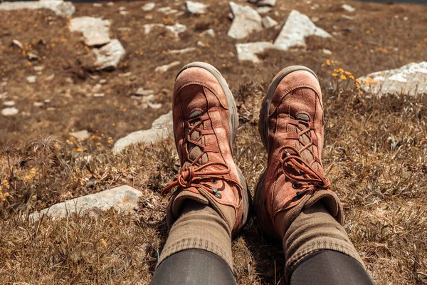 Female hiker feet in trekking boots relaxing after a long hike on the top of a mountain on sunny day. Vacation and travel. Carpathians, Ukraine