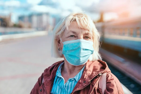 Femme adulte caucasienne portant un masque médical pour se protéger contre la pollution et les virus pendant qu'elle est à la gare en attendant le transport pour voyager — Photo