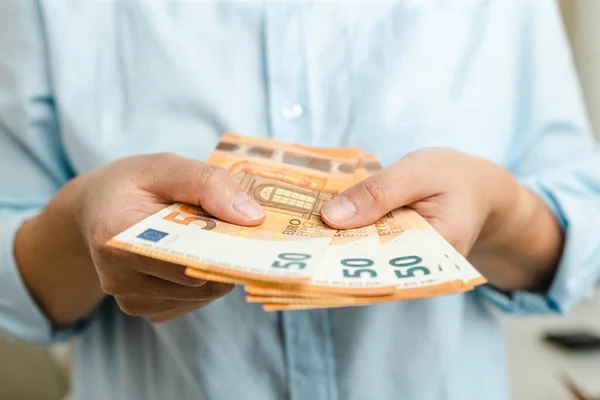 Руки женщины с деньгами евро на сером фоне — стоковое фото