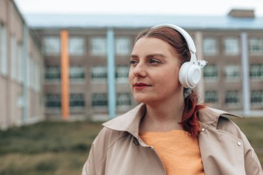 Genç havalı bayan kulaklıkla müzik dinliyor.