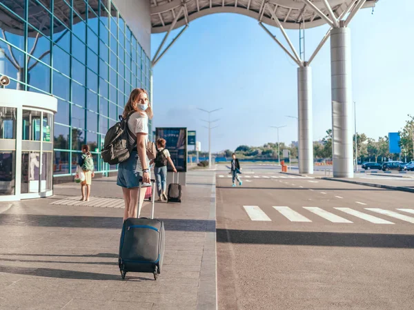 COVID-19 reizen luchthaven vrouw toerist met rugzak en handbagage koffer staan in de buurt van de internationale luchthaven terminal te wachten voor boarding. Actieve levensstijl — Stockfoto