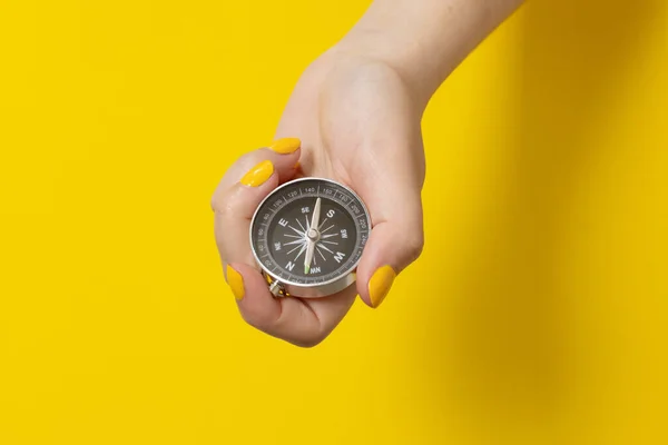 Mão feminina segurando uma bússola em um fundo amarelo. Viagem, estilo de vida de aventura. Estrada para casa. Viagem. — Fotografia de Stock