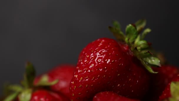 Frutos de morango maduros vermelhos orgânicos frescos em um fundo escuro, close up. Gota pura de água líquida na baga — Vídeo de Stock