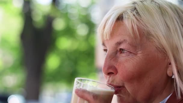 Primer plano retrato de la mujer mayor rubia feliz disfrutando de beber café aroma con leche mirando hacia el café por la mañana. — Vídeo de stock