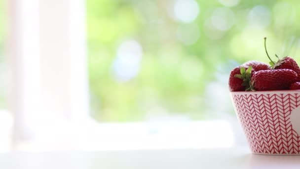 Közelről a női kéz vesz érett epret egy tálból az asztalon — Stock videók