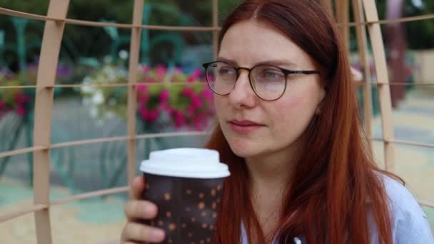 Primer plano de mujer joven sosteniendo taza de papel de café y disfrutar de la bebida en la calle, llevar. Mujer de negocios con camisa elegante y gafas de vista — Vídeo de stock