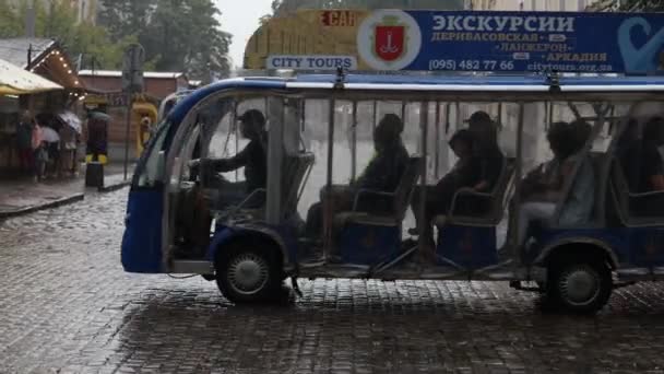 โอเดสซา, ยูเครน, 23 สิงหาคม 2021: ฝนตกหนักพร้อมลมและน้ําจํานวนมาก รถท่องเที่ยวที่มีนักท่องเที่ยวผู้คนขี่ในสายฝนตามถนนในเมือง — วีดีโอสต็อก