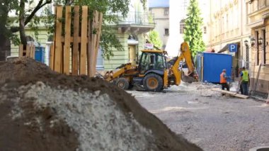 Lviv, Ukrayna, 5 Temmuz 2021: Yolu açmak için toprağı kazan sarı büyük kova kazıcı. Kazı kovası toprağı kazıyor.
