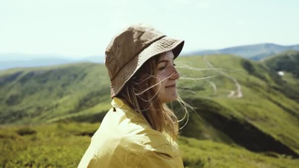 Krásná turistka dívka s vlasy foukání ve větru těší čerstvý vzduch v horní hoře — Stock video