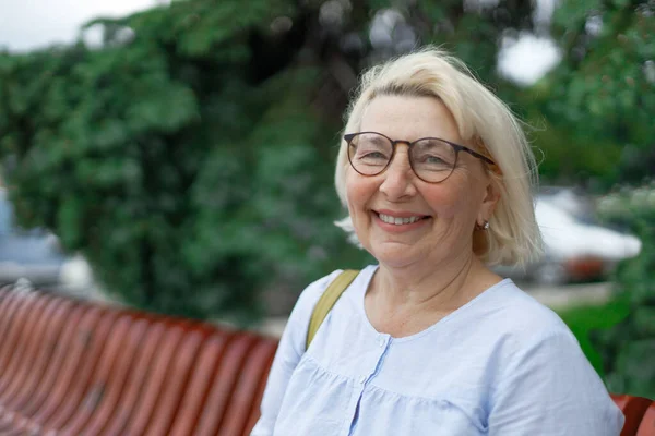 Souriant blonde prof femme dame 40s 50 ans portant des lunettes debout tenir des blocs-notes regardant caméra à l'extérieur — Photo