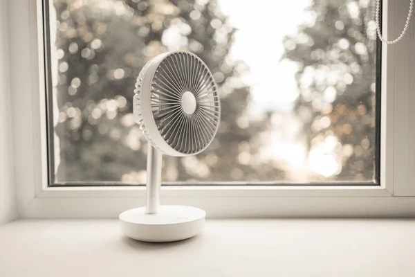 Modern electric portable fan in bedroom at home. Cooling of high air temperature. Minimal style, copy space.