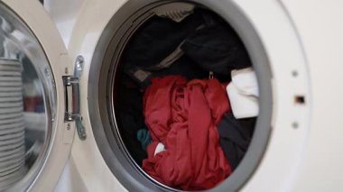 Kadın eli çamaşır makinesine siyah ipek elbiseler koyuyor, yakın plan. Yüksek kaliteli FullHD görüntüler