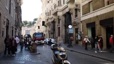 İtalya 'nın tarihi Roma şehir merkezinde Avrupa' nın kaldırım taşı sokağında. Dar caddelerde scooterlar, park edilmiş araçlar ve eski kasabadan geçen itfaiye kamyonu ile yürüyen yayalar. Kentsel