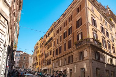 Roma, İtalya - 3 Ekim 2025: Roma şehir merkezinde güneşli bir günde tarihi konut binaları yakınlarındaki bir caddeden geçen yayalar.