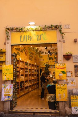 Roma, İtalya - 4 Ekim 2025: Roma 'da limonlar ve yeşilliklerle süslenmiş parlak sarı limonata dükkânı girişi içinde raflar dolusu şişe posteri ve küçük bir tadımlık alan bulunuyor.